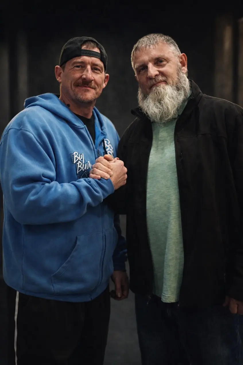 Two men sharing a friendly handshake portrait at an event